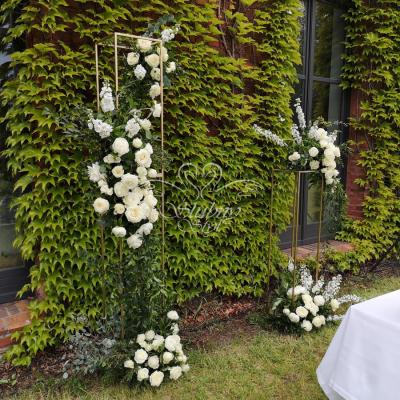 Złote stojaki geometryczne z kwiatami na ślub plenerowy