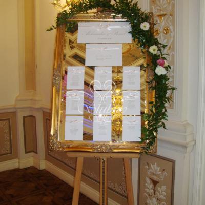 Girlanda dekoracją tablicy z rozmieszczeniem gości - lustro w złotej ramie