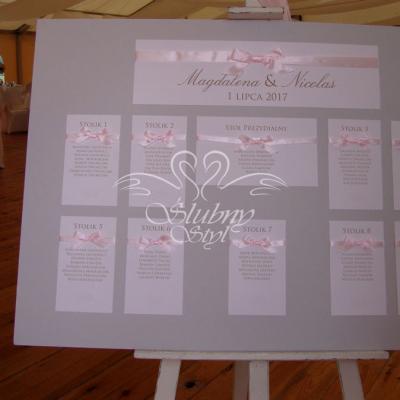 Delikatnie popielata tablica z rozmieszczeniem gości - karteczki z nazwiskami przepasane różową wstążeczką