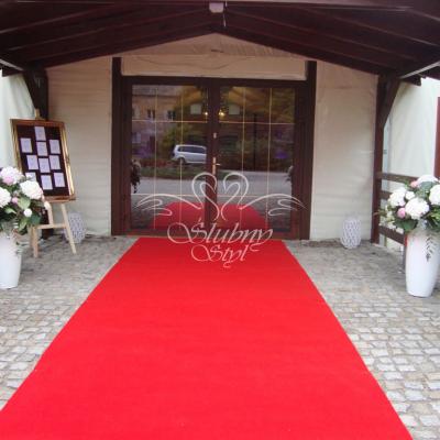 Czerwony welurowy dywan i duże kompozycje kwiatowe na wejściu do sali weselnej - Pałac Jabłonowo 