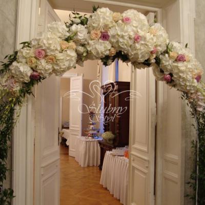 Ślubny łuk z żywymi kwiatami na wejściu do sali weselnej