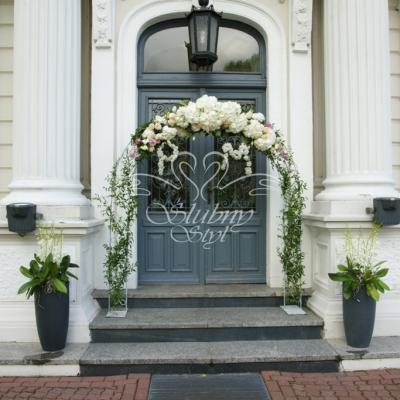 Inicjały z żywych kwiatów na tle bramki kwiatowej