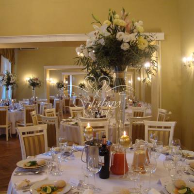 Na okrągłych stołach wysokie bukiety z lilii i eustomy w szklanych stożkach