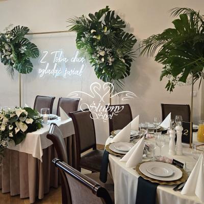 Złote podtalerze i czarne serwetki materiałowe w dekoracjach sali weselnej