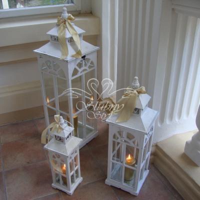 Białe drewniane lampiony ze złotą świeczką na tarasie