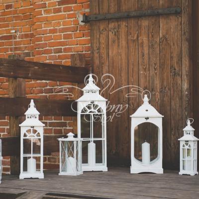 Białe drewniane lampiony różnej wielkości na wejściu