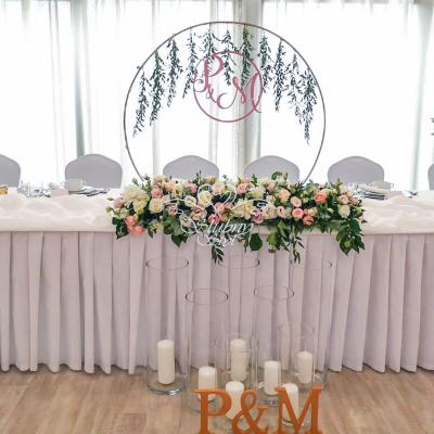 Świeczki w szklanych tubach i inicjały przed stołem młodych