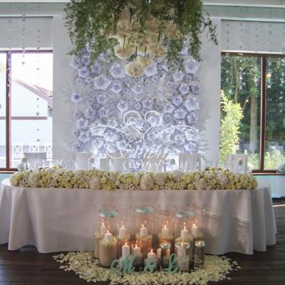 Nastrojowe świeczki w tubach w towarzystwie żywych płatków róż przed stołem Młodej Pary