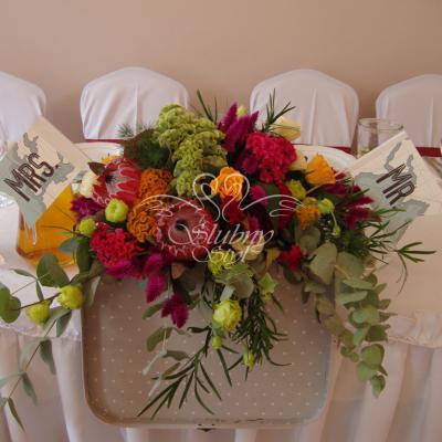 Kompozycja kwiatowa w walizce na stole Młodej Pary - kolorowe celozje 