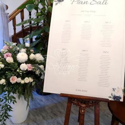 Okazały bukiet w wysokim wazonie przy tablicy z rozmieszczeniem gości