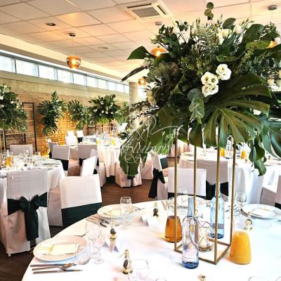 Numerki stołów w kompozycjach na liściach monstery - wesele