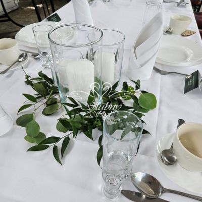 Zestaw 3 szklanych tub ze świeczkami z dodatkiem zieleni jako dekoracja na weselu