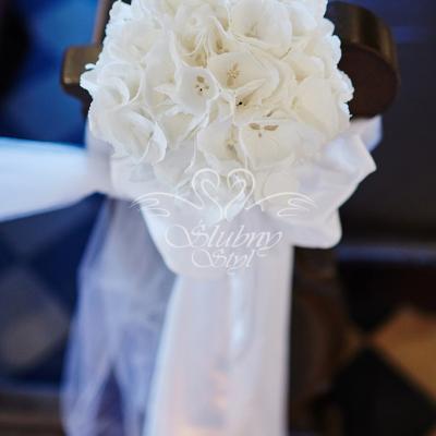 Dekoracja ławki w kościele białą hortensją i wstążką