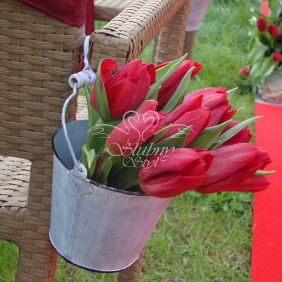 Dekoracyjne wiaderka z kwiatami przy ratanowych krzesłach